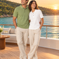 Models in Meraki green and Kalon white Northmist organic polo t-shirts on a yacht deck along a green coastline