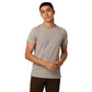 A person with short black hair, wearing a stylish light grey Amity Combo Pack: Organic Crew Neck T-shirt - Grey and Mustard by Northmist and dark brown pants, stands against a plain white background. They have a neutral expression, and their hands are clasped in front of them.
